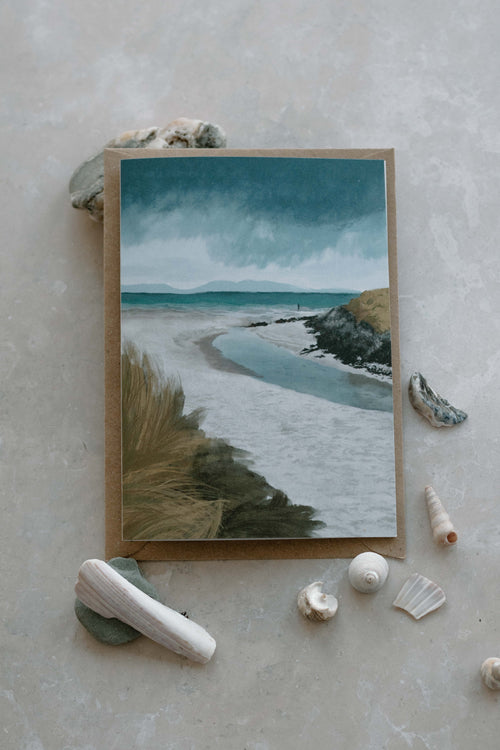 Card of a coastal scene with shells and rocks on a textured surface