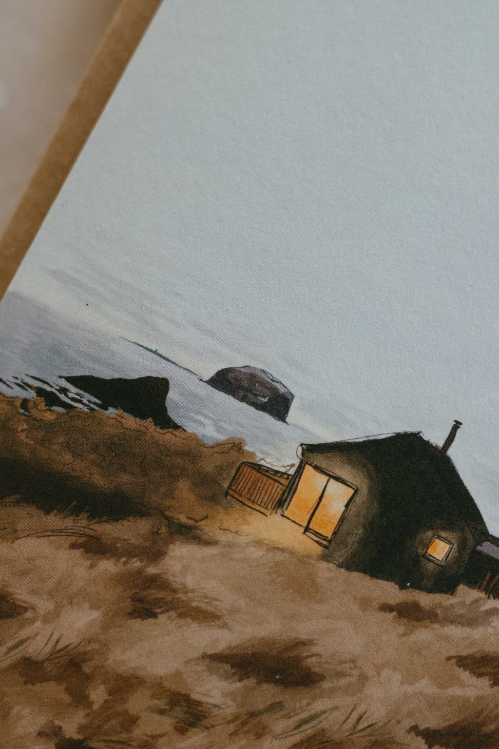 Artistic depiction of a small cabin on a beach landscape with the sea in the background.