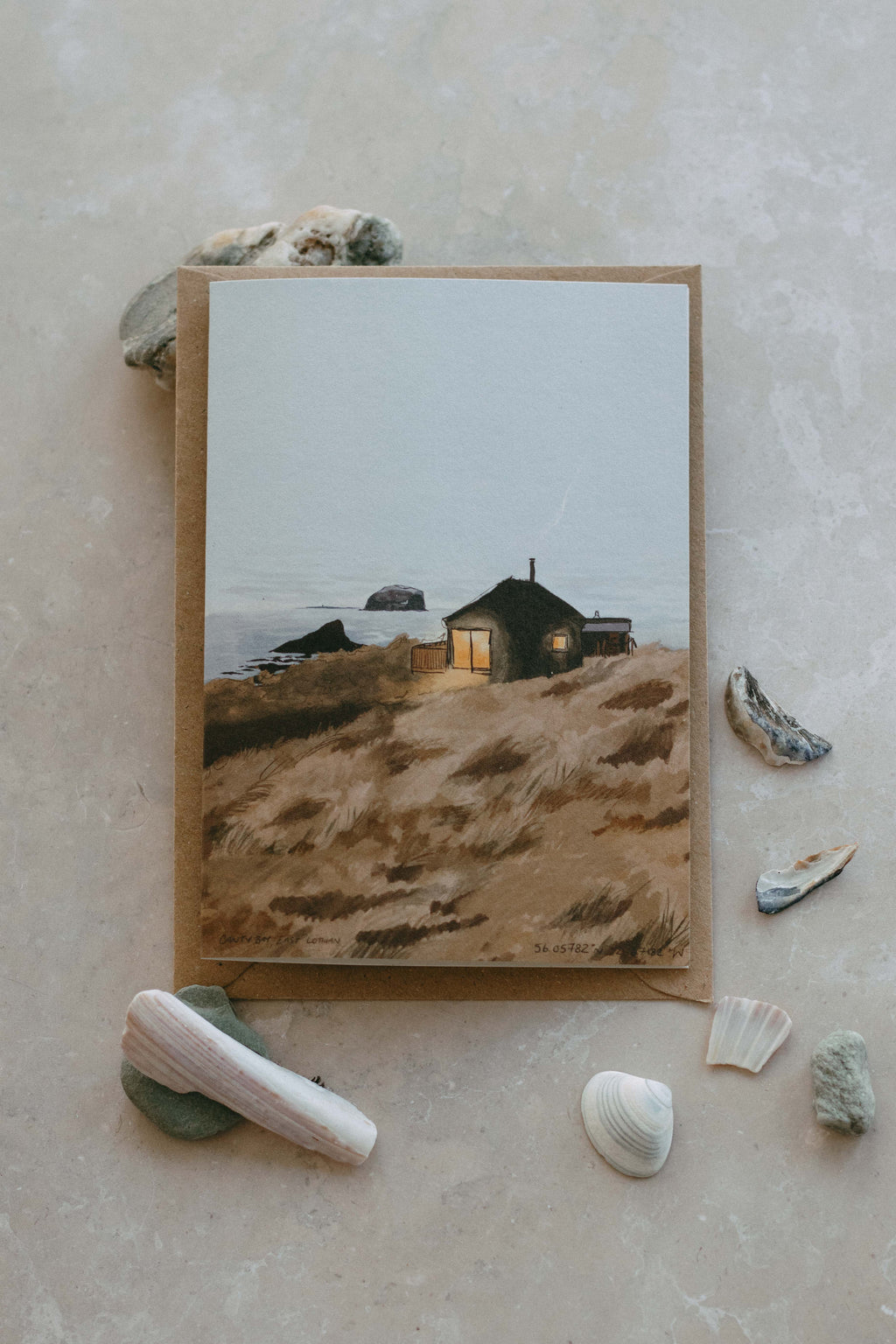 Illustration of a coastal scene with a house on the dunes, surrounded by seashells on a textured beige surface.