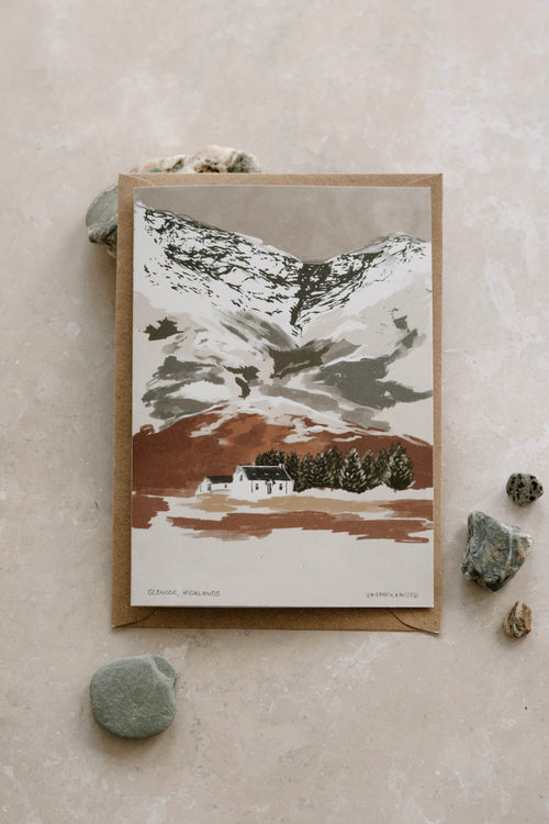Greeting card with mountain landscape design on a textured surface with stones.