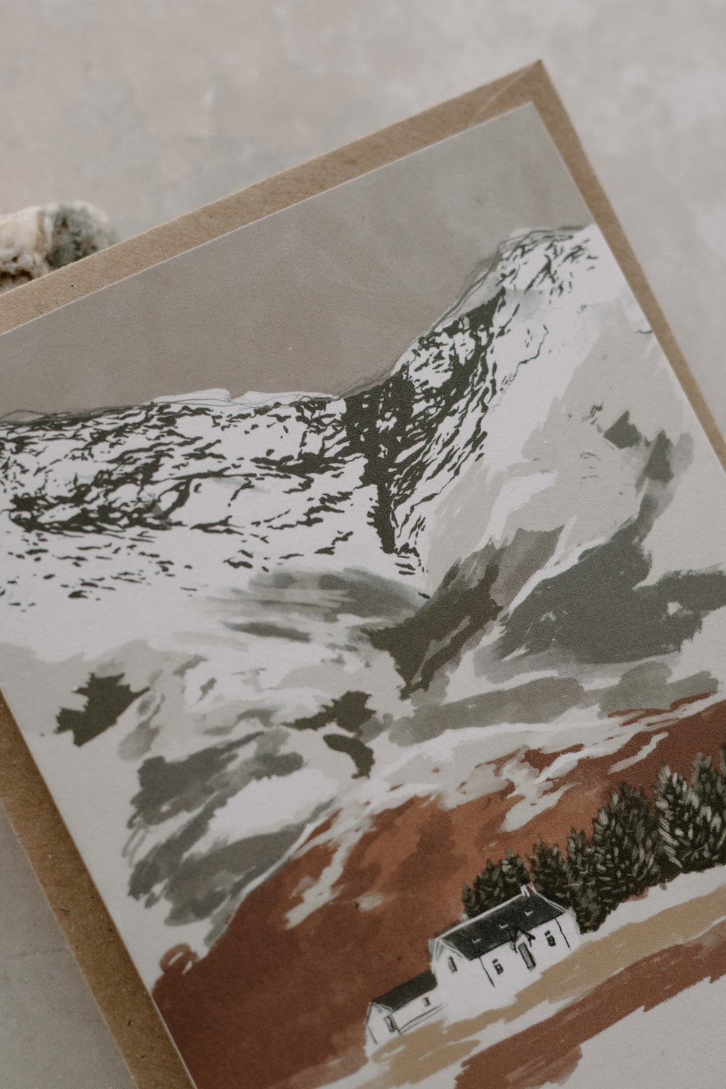 Greeting card with a mountain landscape and cottage design with snow dusted mountains.