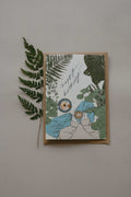 Greeting card with plant-themed design and a fern leaf on a plain background