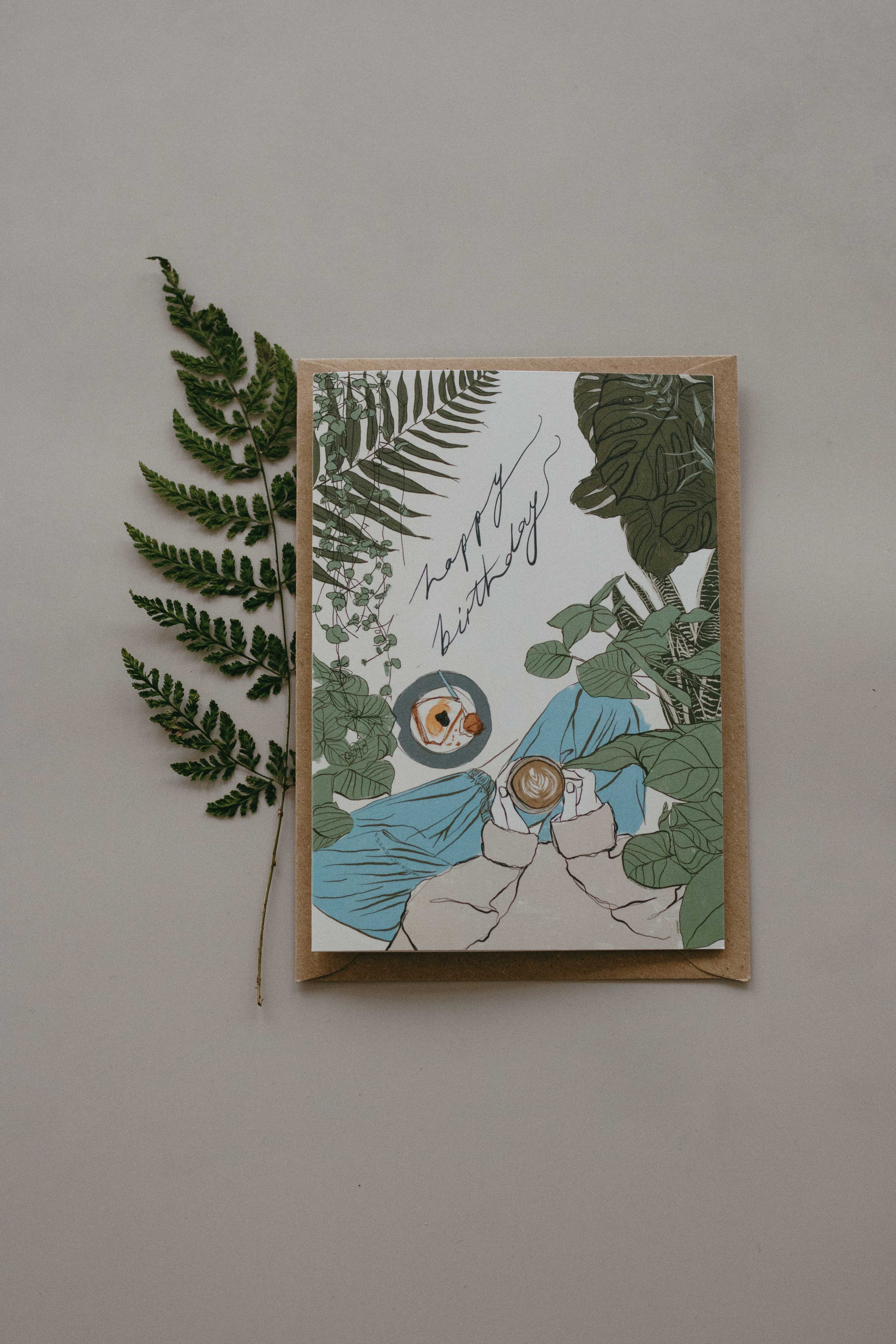 Greeting card with plant-themed design and a fern leaf on a plain background