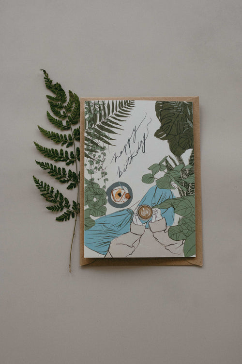 Greeting card with plant-themed design and a fern leaf on a plain background