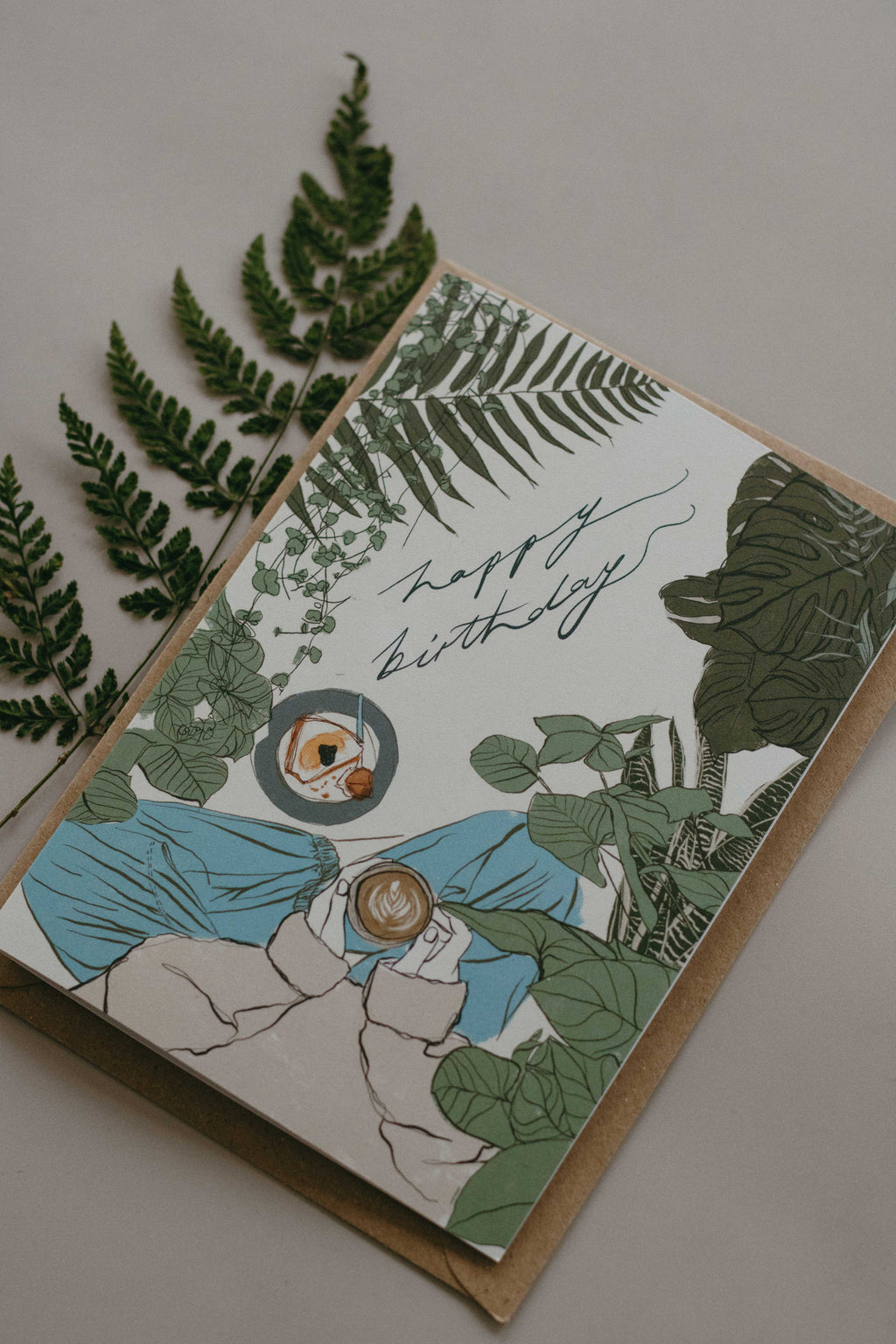 Greeting card with house plant design and 'Happy Birthday' text, surrounded by green foliage