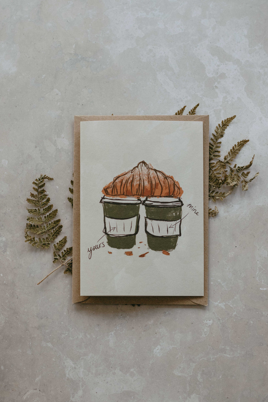 Card with illustration of two coffee cups and a pastry on a textured surface with leaves.